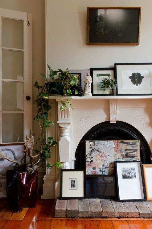 a vintage fireplace with an arrangement of artworks, with potted plants and a statue is a beautiful idea for a refined feel