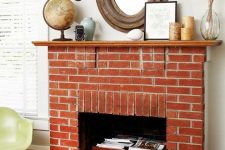 a vintage red brick fireplace with a wooden chest that is used for books and magazine storage, with pretty vintage decor on the mantel