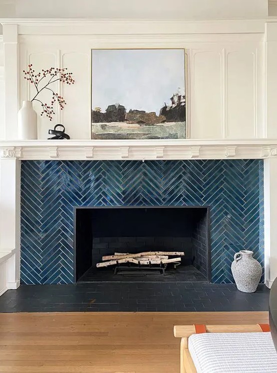 an elegant fireplace clad with navy herringbone tiles, with a mantel and some decor is a lovely idea for a modern space