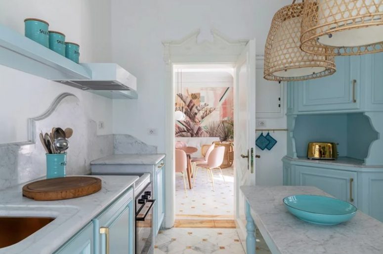 The kitchen is done with beautiful blue cabinets, white marble countertops and backsplashes and rattan pendant lamps