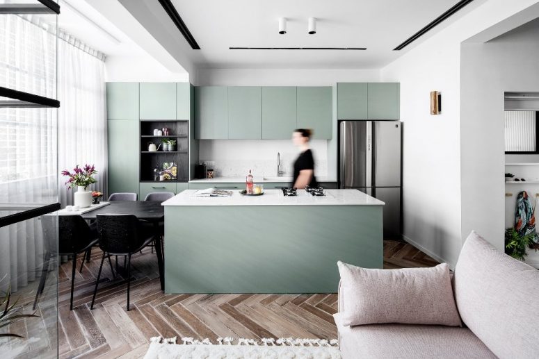 The kitchen and dining zone are also here, the cabinets are green ones, with mable countertops and a backsplash, a black dining table and chairs The kitchen and dining zone are also here, the cabinets are green ones, with mable countertops and a backsplash, a black dining table and chairs