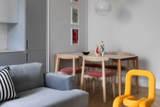 04 The dining space is done with a wooden table, pink chairs and bold artworks and pendant lamps