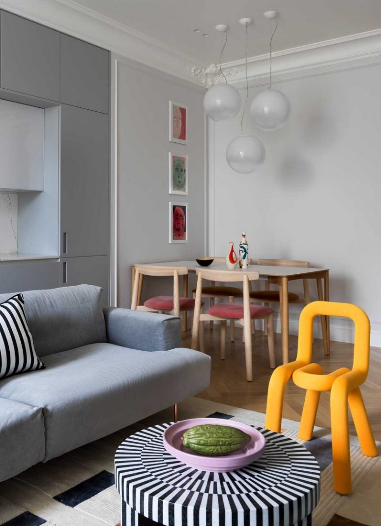 The dining space is done with a wooden table, pink chairs and bold artworks and pendant lamps