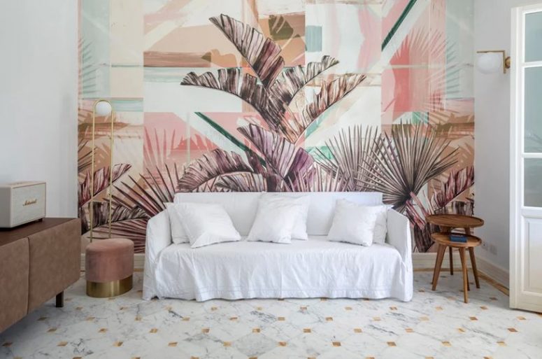 The living room features a simple white sofa, some elegant vintage furniture and a gorgeous palm statement wall