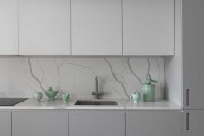 05 The kitchen is done in two shades of grey, with a marble backsplash and countertops