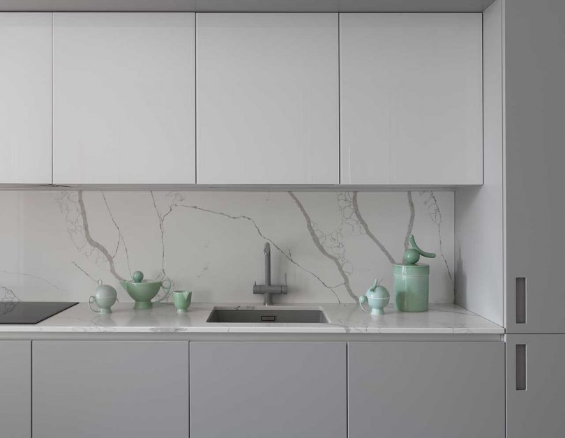 The kitchen is done in two shades of grey, with a marble backsplash and countertops
