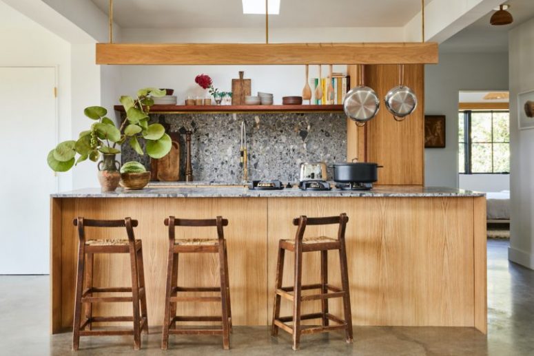 kitchen with cool terrazzo surfaces The kitchen is done with light-colored cabinets and grey terrazzo surfaces plus a hanging shelf over the kitchen