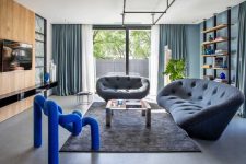 05 The living room is done with slate grey sofas, an industrial shelf and a gorgeous electric blue chair that steals the show