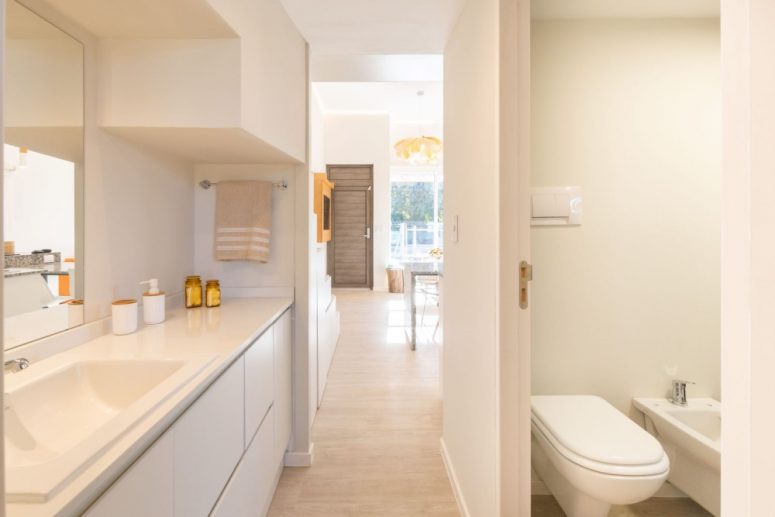 The bathroom is very small and sleek and is done in light colors to make it feel spacious and airy
