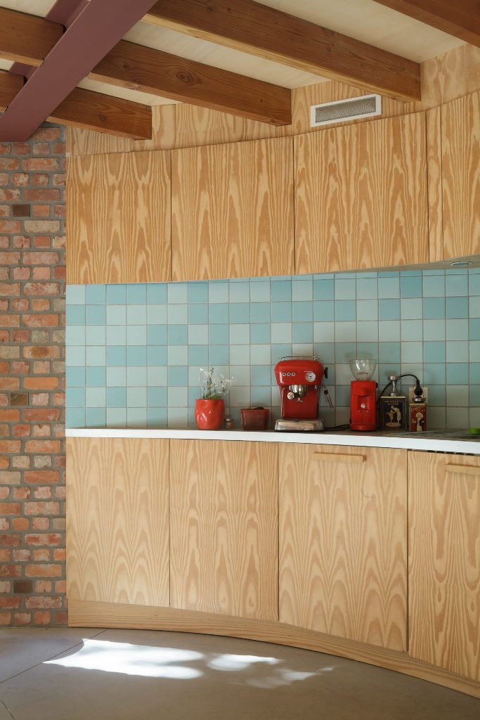 Two-tone blue tiles form a kitchen splashback and   plus bright red appliances help to create a mid-century modern feel