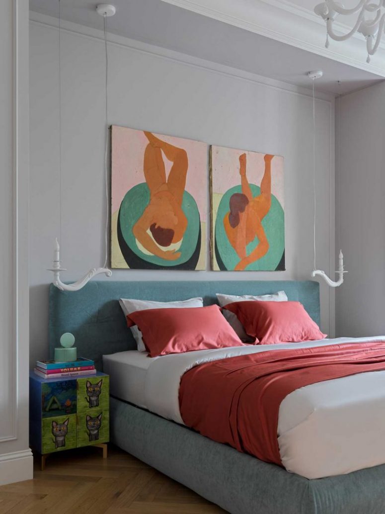 The bedroom shows off a grey upholstered bed, colorful nightstands and bold artworks