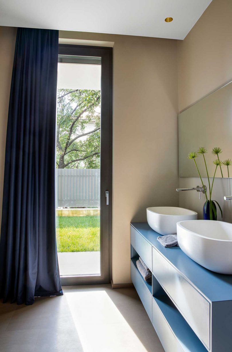 The bathroom is done with a blue double vanity, a navy curtain may be used for privacy