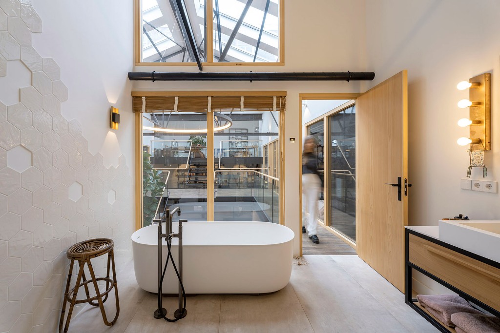 The bathroom is simple and minimalist, with large windows, an oval tub and a large vanity