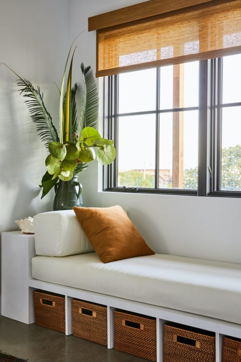 There's a window daybed with storage unit it that is also accented with a statement plant arrangement
