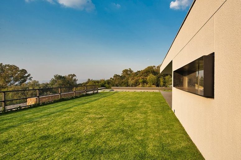 The living room lawn terrace is positioned on top of the service level, buried below the landscape