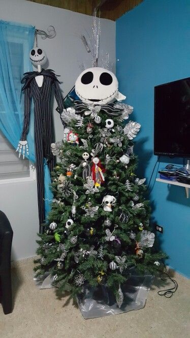 a Christmas tree decorated with Nightmare Before Christmas ornaments and with Jack Skellington standing next to it