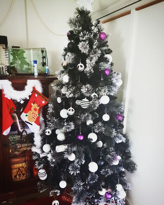 a beautiful flocked black Christmas tree with white and purple ornaments plus Jack Skellington ones is a bright and contrasting idea to rock