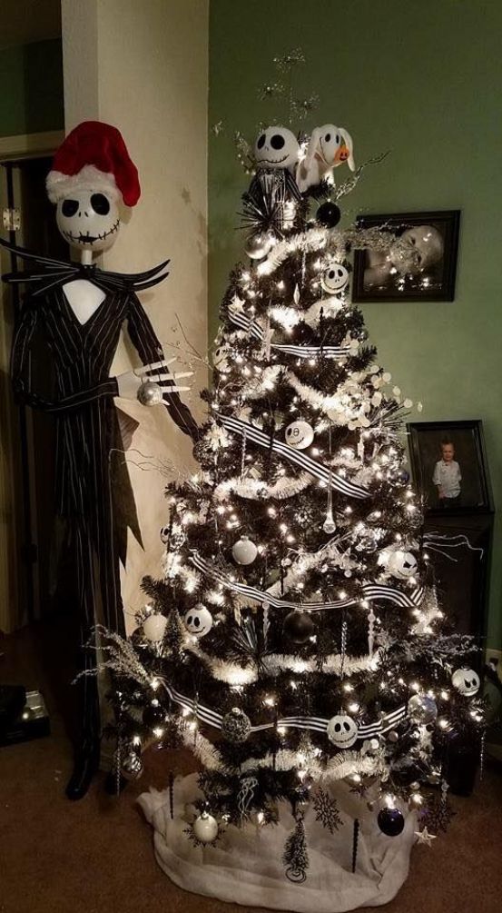 a black Christmas tree with black and white ribbons, white garlands, lights and black and white Skellington ornaments plus Jack Skellington next to it