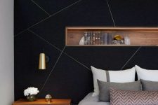 a black accent with gold geometric patterns and a wooden niche with books is a stylish idea for making a statement in a bedroom