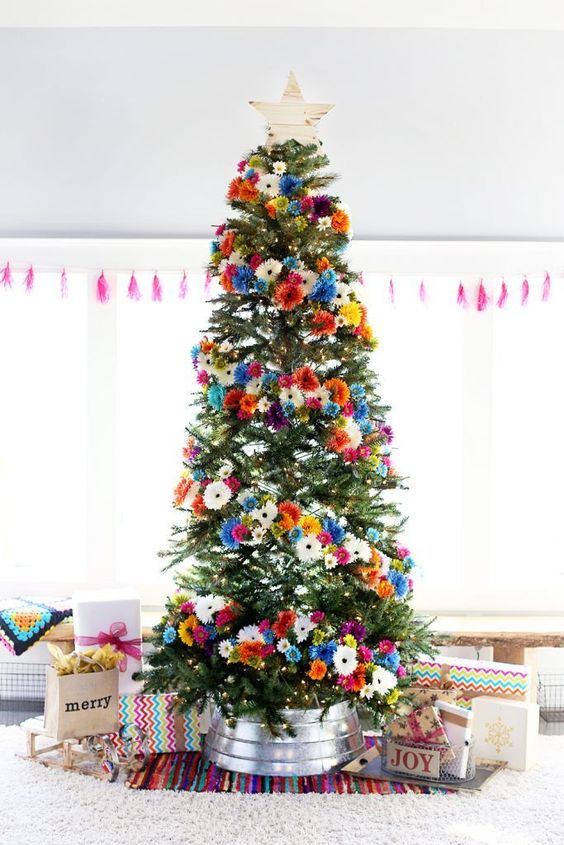 a bright Christmas tree with orange, pink, blue, white and yellow faux blooms and a wooden star topper is gorgeous