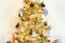 a chic and beautiful Christmas tree in a basket, with pinecones, mini tree-shaped ornaments, snowflakes and lights plus a star topper
