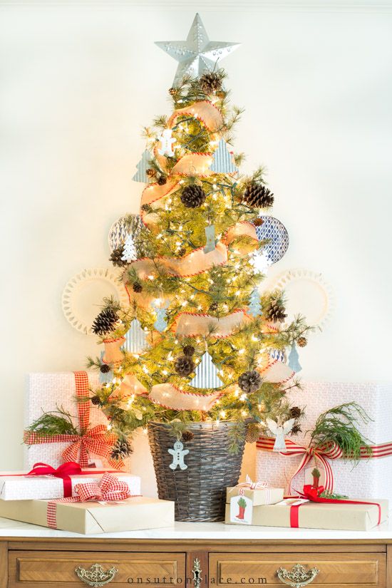 a chic and beautiful Christmas tree in a basket, with pinecones, mini tree-shaped ornaments, snowflakes and lights plus a star topper