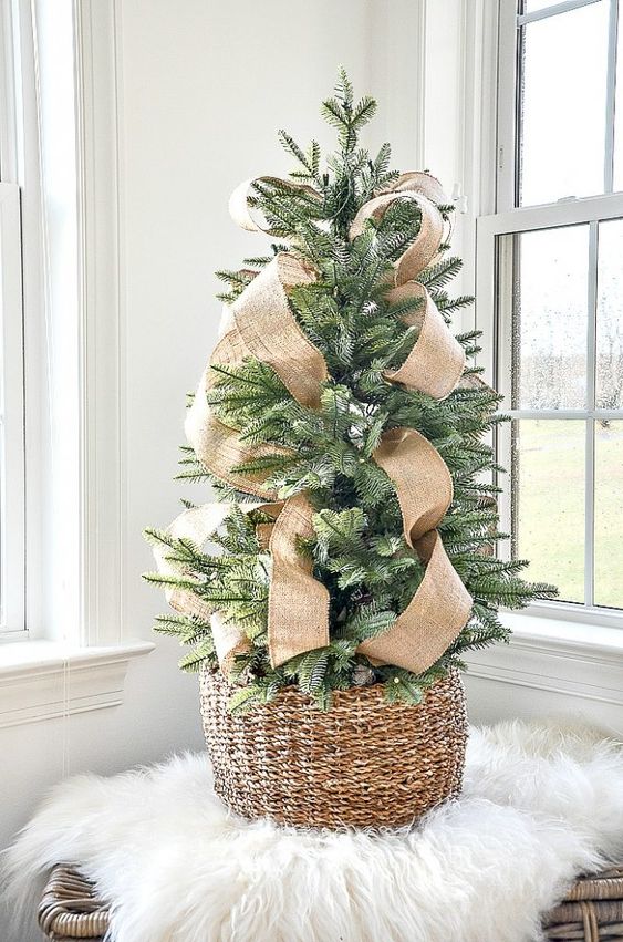 a chic and simple tabletop Christmas tree in a basket with burlap ribbons is a lovely idea with a slight and elegant rustic feel