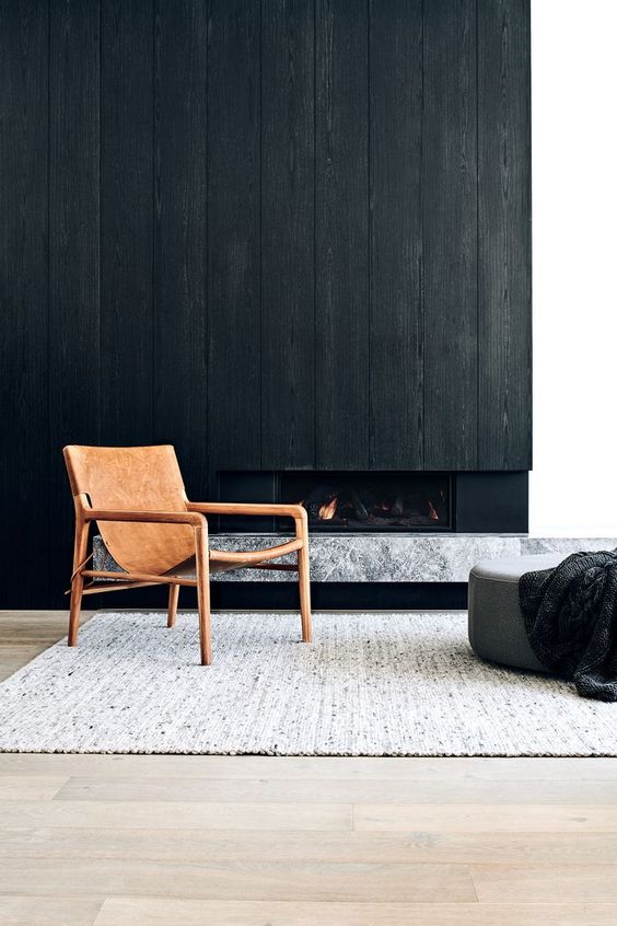 a dramatic wooden wall with a built-in fireplace and a marble slab mantel under it is a chic solution for a minimalist space