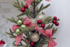 a pretty tabletop Christmas tree with green, red and shiny metallic ornaments and plaid bows plus a burlap sack for a rustic feel