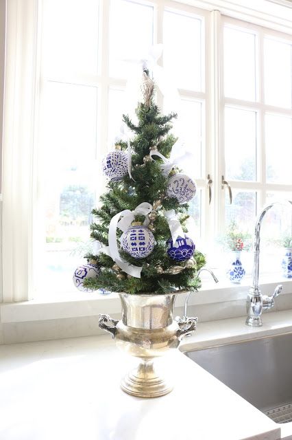a tabletop Christmas tree in a vintage urn, with white ribbon bows and blue and white Christmas ornaments is a lovely and vintage idea