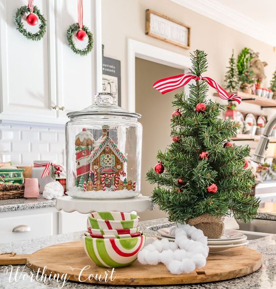 a tabletop Christmas tree in burlap, with red ornaments, a red and white striped ribbon on top is a lovely and chic idea