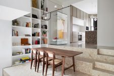 02 There’s a large open shelving unit built-in on the left, a cozy wooden dining set on the steps
