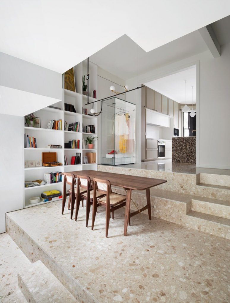 There's a large open shelving unit built-in on the left, a cozy wooden dining set on the steps