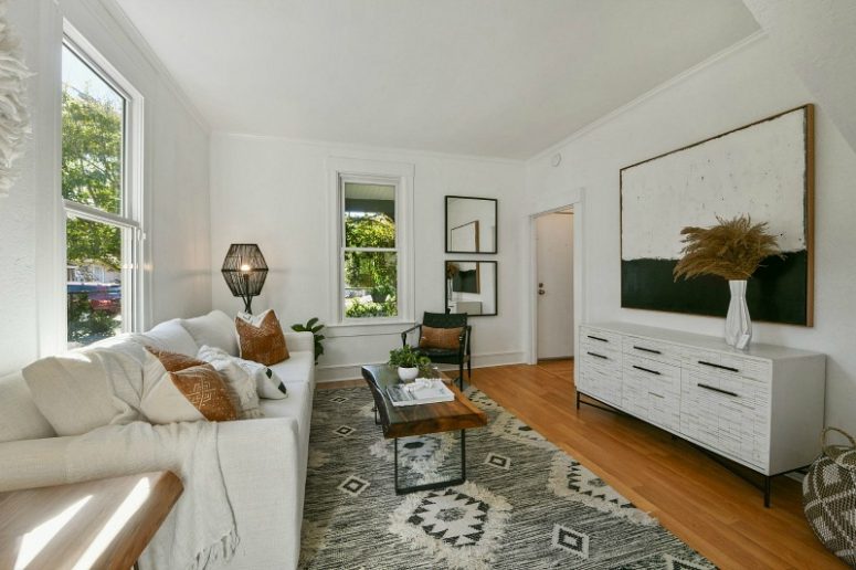 The living room features a monochromatic color scheme, chic furniture, a couple of mirrors and a boho rug The living room features a monochromatic color scheme, chic furniture, a couple of mirrors and a boho rug