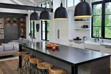 04 The kitchen is done with white cabinetry, with a dark kitchen island, pendant lamps and wooden stools