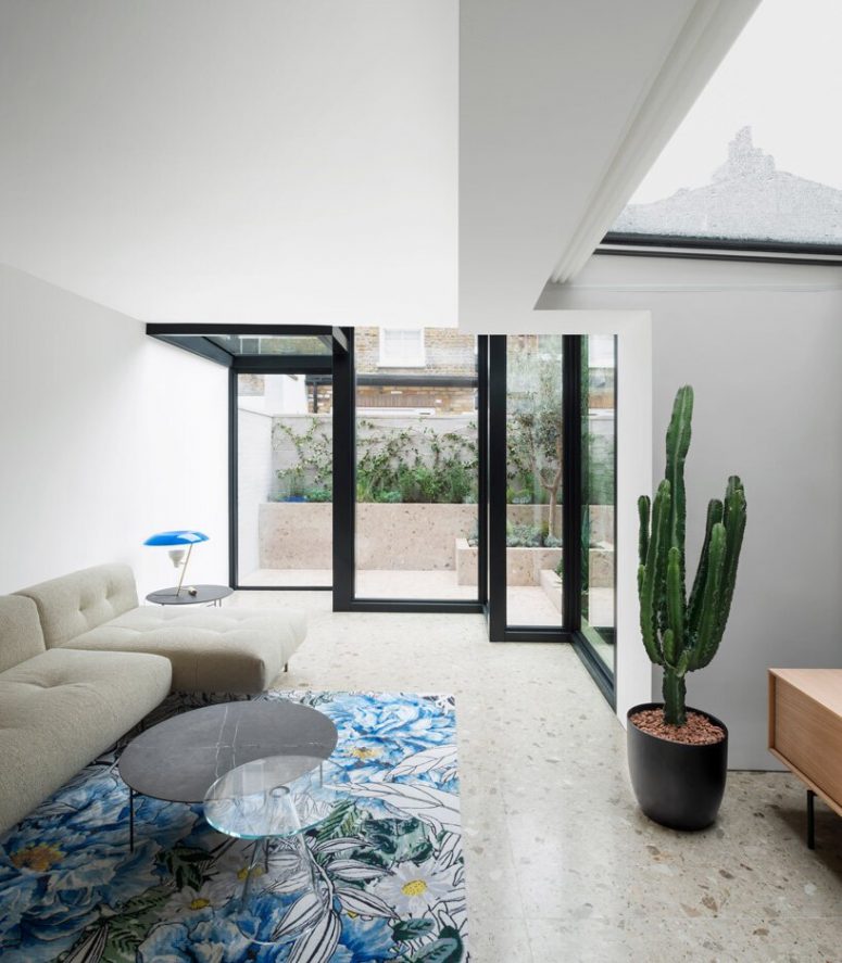 The living room shows off a sectional, a bright rug and a couple of chic tables