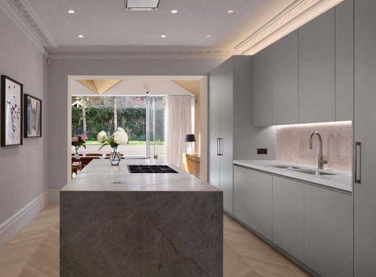 The kitchen is minimalist, with sleek white cabintery and a marble kitchen island