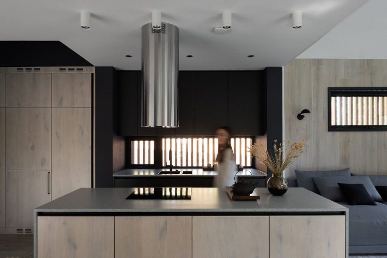 The kitchen shows off neutral wooden cabinetry and some black cabinets, too