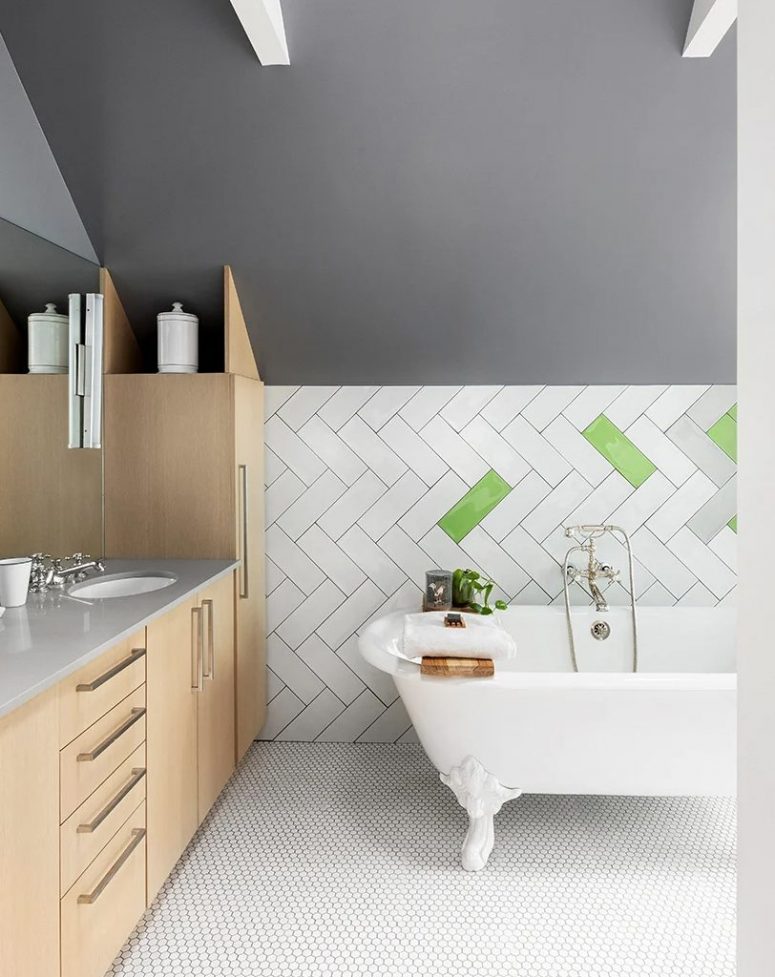The bathroom is eye-catchy, with grey walls, boldly clad tiles, penny tiles on the floor, sleek plywood cabinetry and a vintage tub
