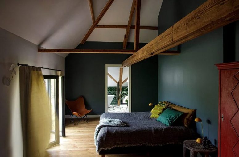 The bedroom is moody, with hunter green walls, bright textiles, wooen beams that add charm and a vintage feel The bedroom is moody, with hunter green walls, bright textiles, wooen beams that add charm and a vintage feel