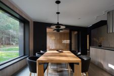 07 The dining zone is done with a wooden table, black chairs and some pendant lamps over the table