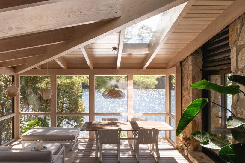 There's a glazed dining room with a fantastic view of the lake and light-colored furniture and pendant lamps