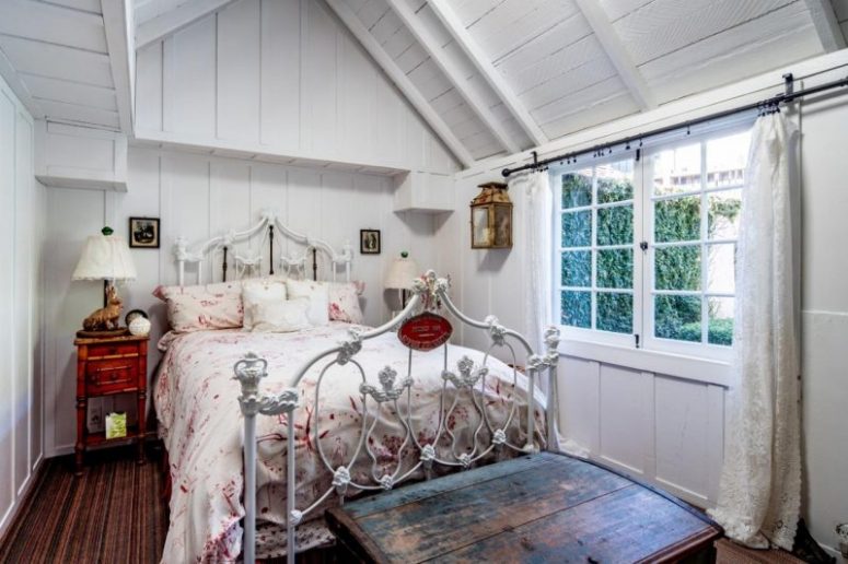 The bedroom is done with a metal bed, dark heavy furniture and floral bedding