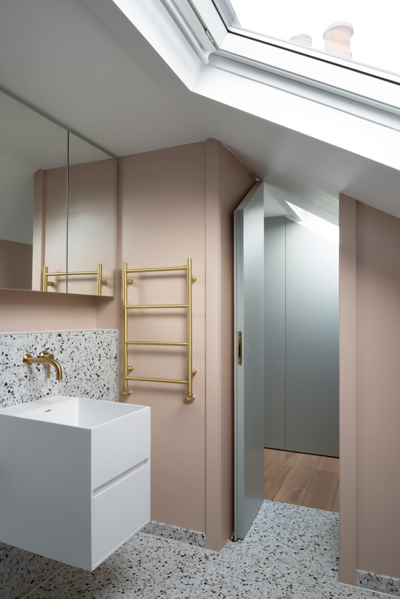 The second bathroom shows off neutral terrazzo, a floating sink and blush walls