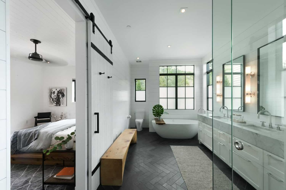 The master suite has a large and stylish bathroom with large windows and a sliding barn door