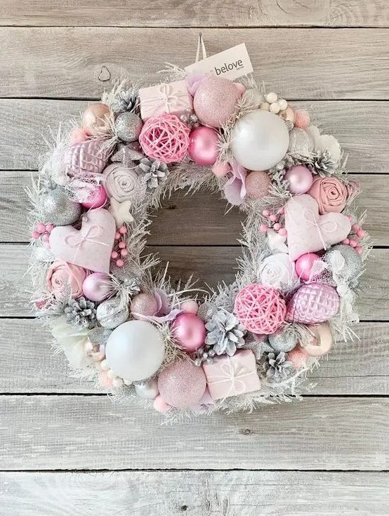a beautiful pastel pink and silver Christmas wreath with hearts, ornaments, snowy pinecones, fluffs and yarn balls is amazing