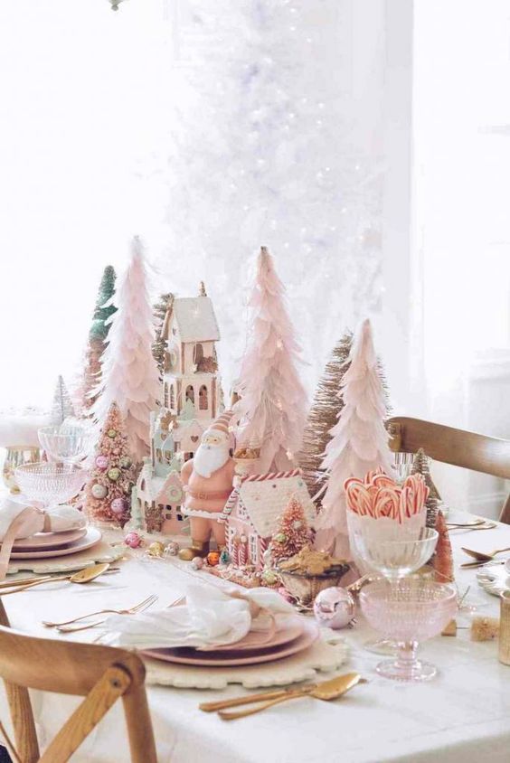 a blush Christmas tablescape with cone trees, a gnome and gingerbread houses, pink plates and gold cutlery