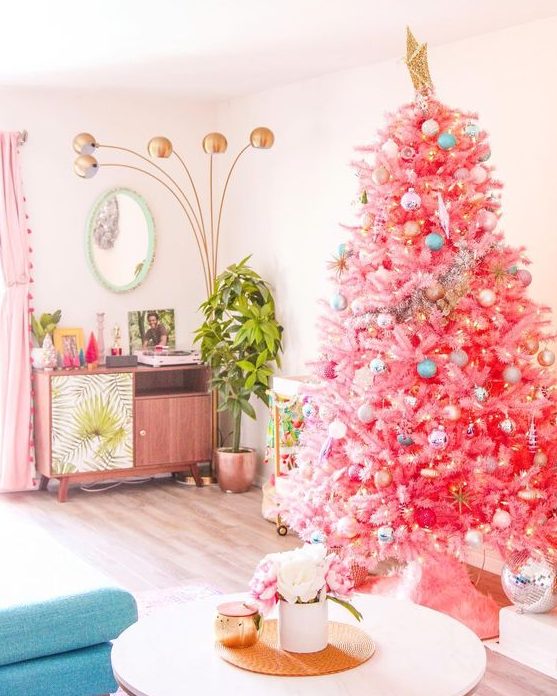 a bright pink Christmas tree with pastel and metallic ornaments and a large gold star topper for infusing your space with color