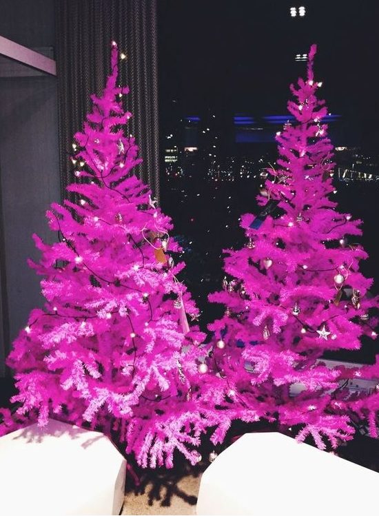 a duo of hot pink Christmas trees decorated with only lights is a fantastic idea for a modenr or minimalist holiday space