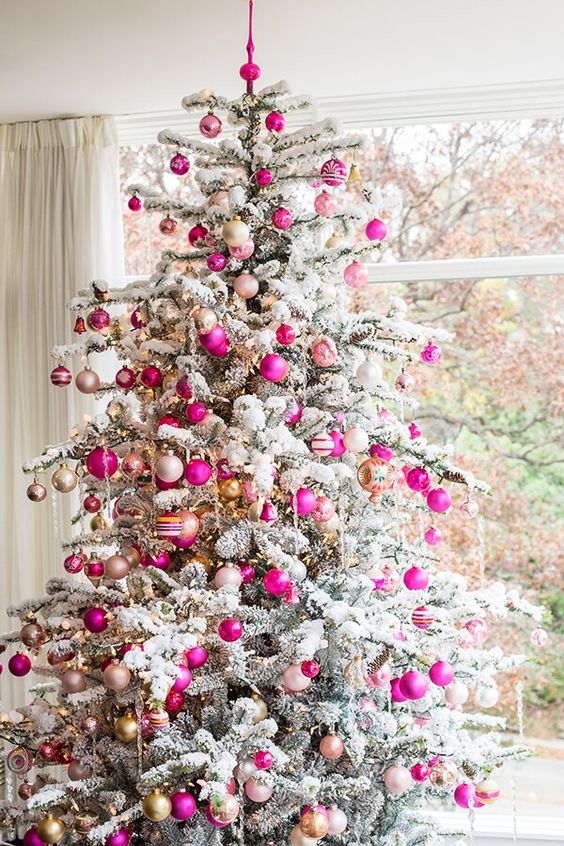 a flocked Christmas tree decorated with neutral, hot pink and blush ornaments and lights looks glam, chic and very modern